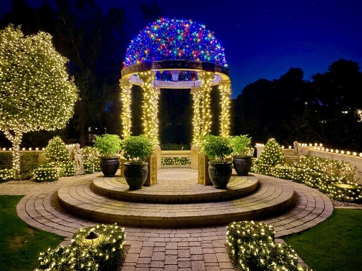Christmas lights on a garden gazebo dome with wrapped trees and hedges in Phoenix