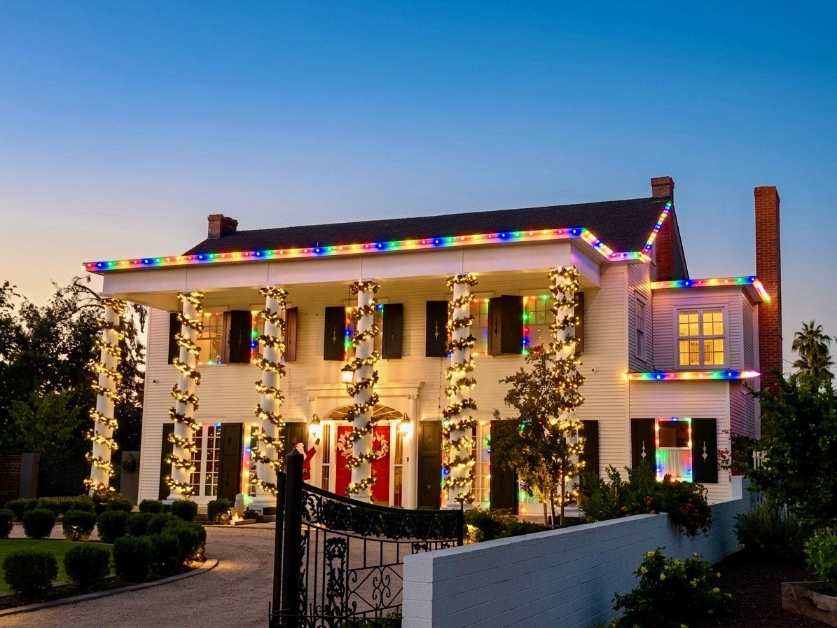 Multicolor Christmas lights on the roofline and garland-wrapped columns of a historic Phoenix home at dusk