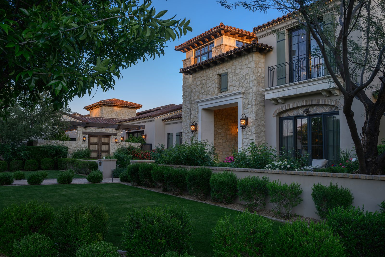 Daytime view of a stucco and stone estate with permanent roofline lighting installed and nearly invisible