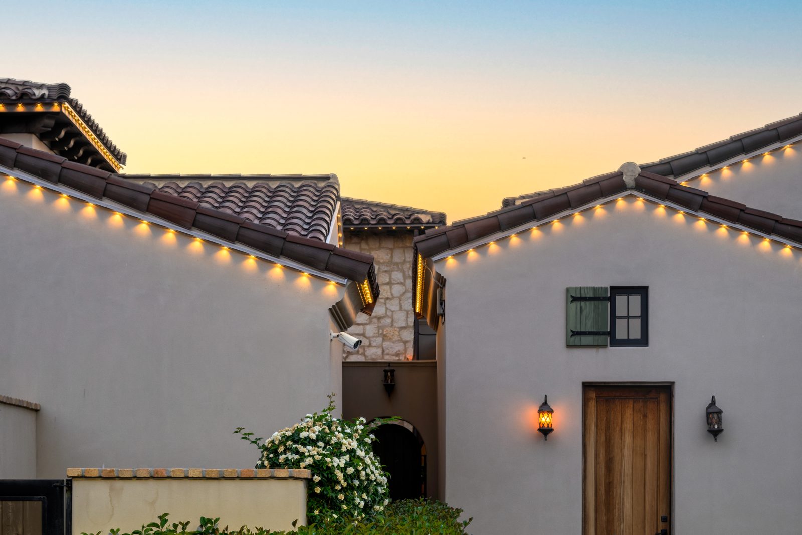 Warm white permanent roofline lighting on segmented tile rooflines at sunset