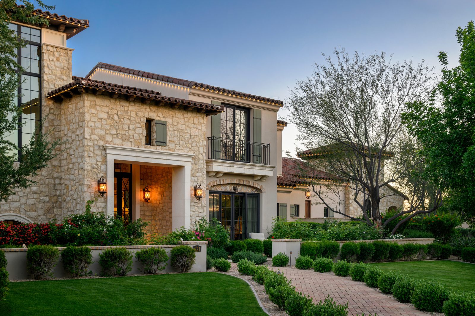 Stone and stucco home at dusk with subtle warm white permanent roofline lighting
