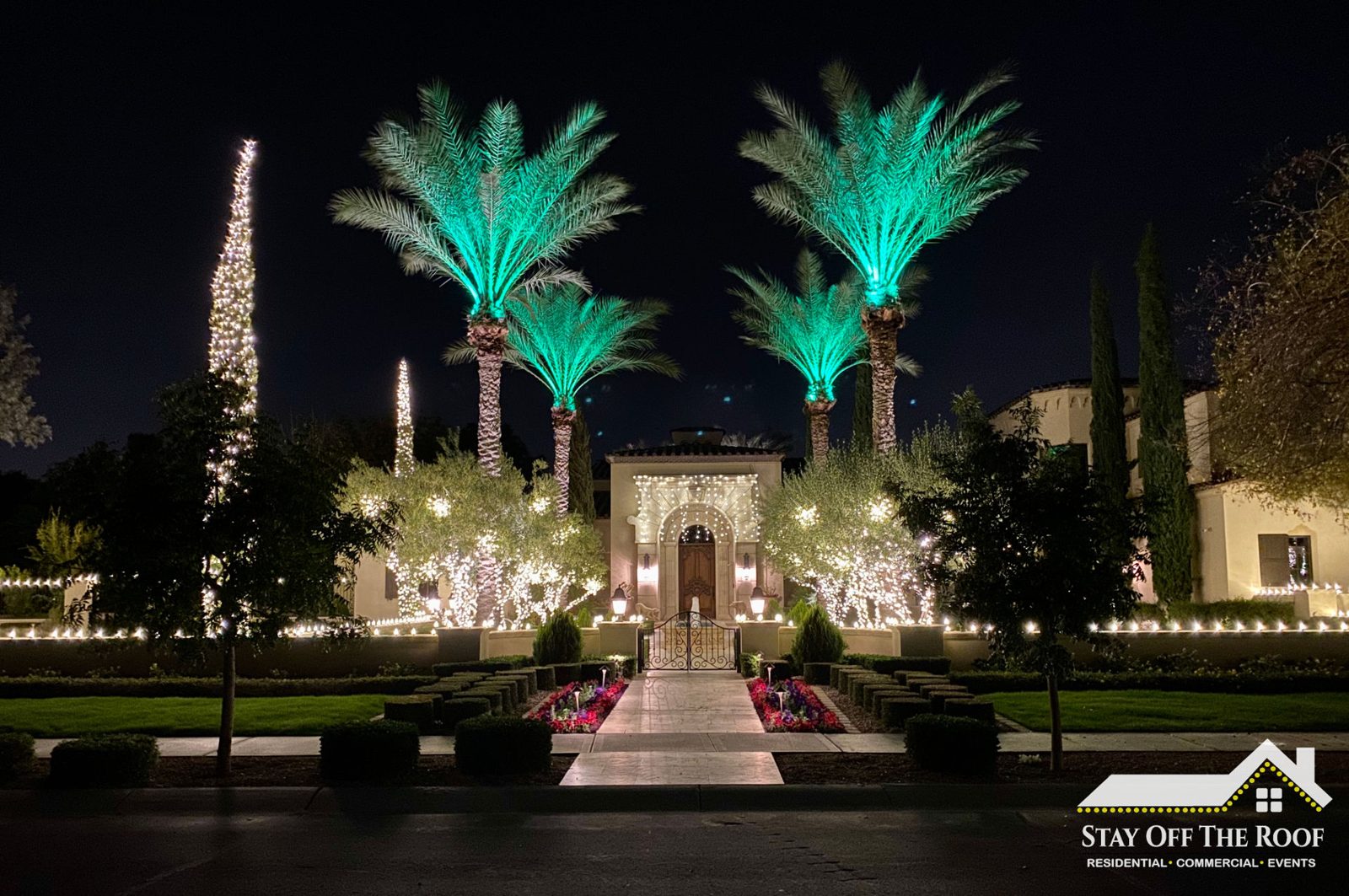Phoenix estate at Christmas with wrapped palms, lit entry and roofline by Stay Off The Roof