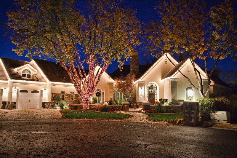 Warm white Christmas roofline lights and a wrapped tree on a Tempe home