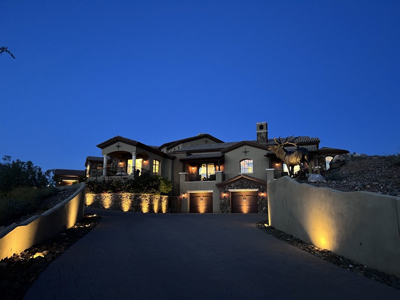 Hillside estate at dusk with warm, downward-aimed driveway and wall lighting