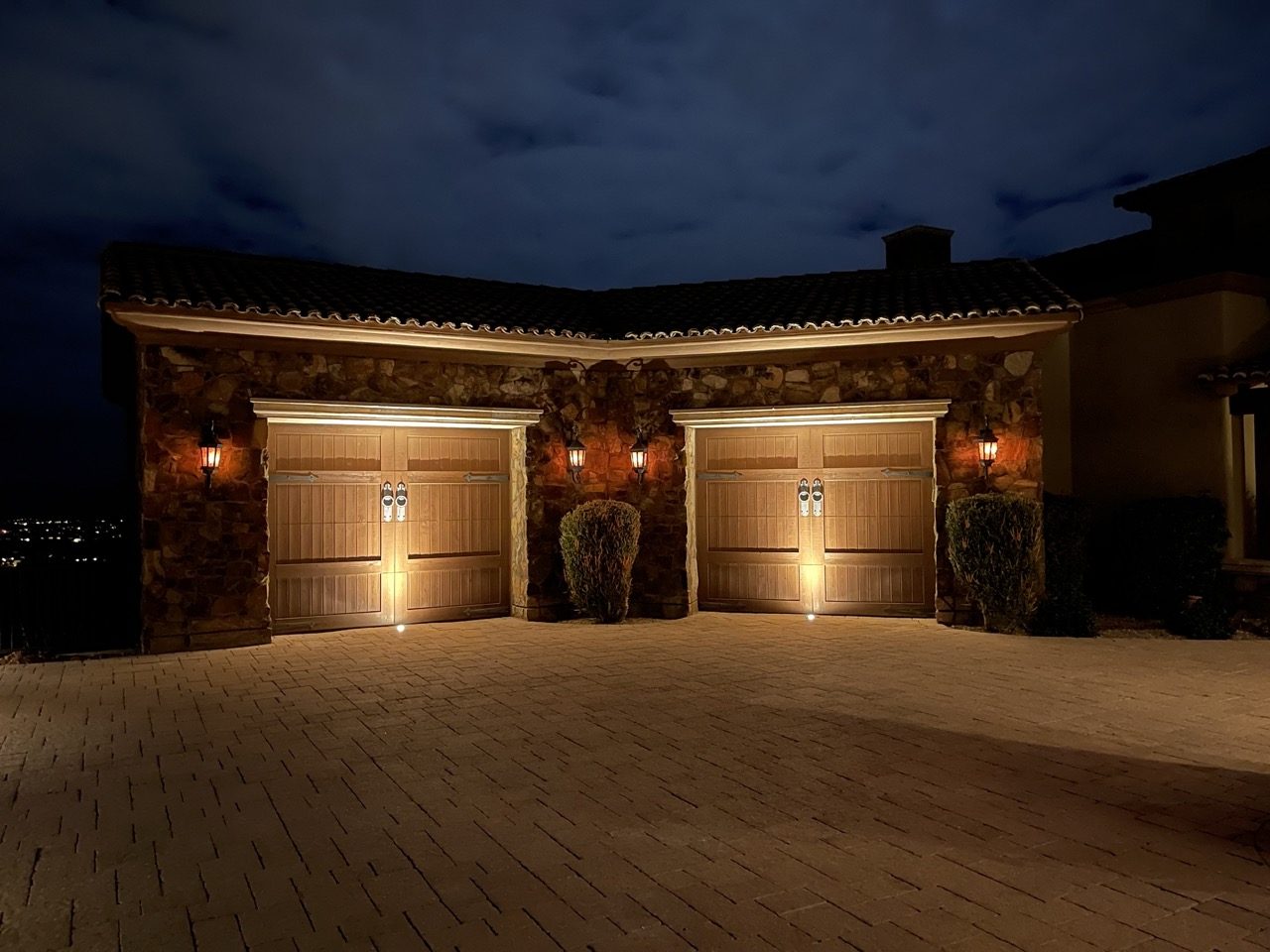 Warm uplighting on wood garage doors and stone columns at night