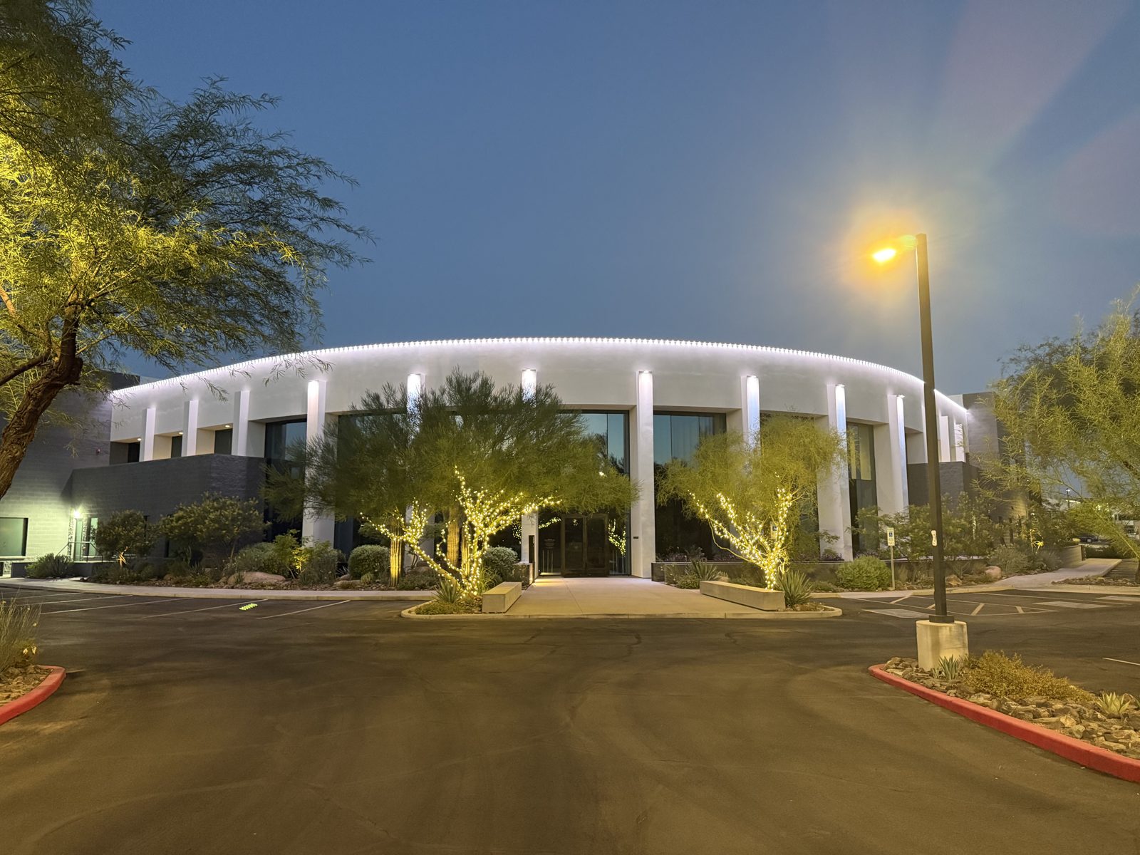 Cool white permanent roofline lighting on a commercial building at dusk