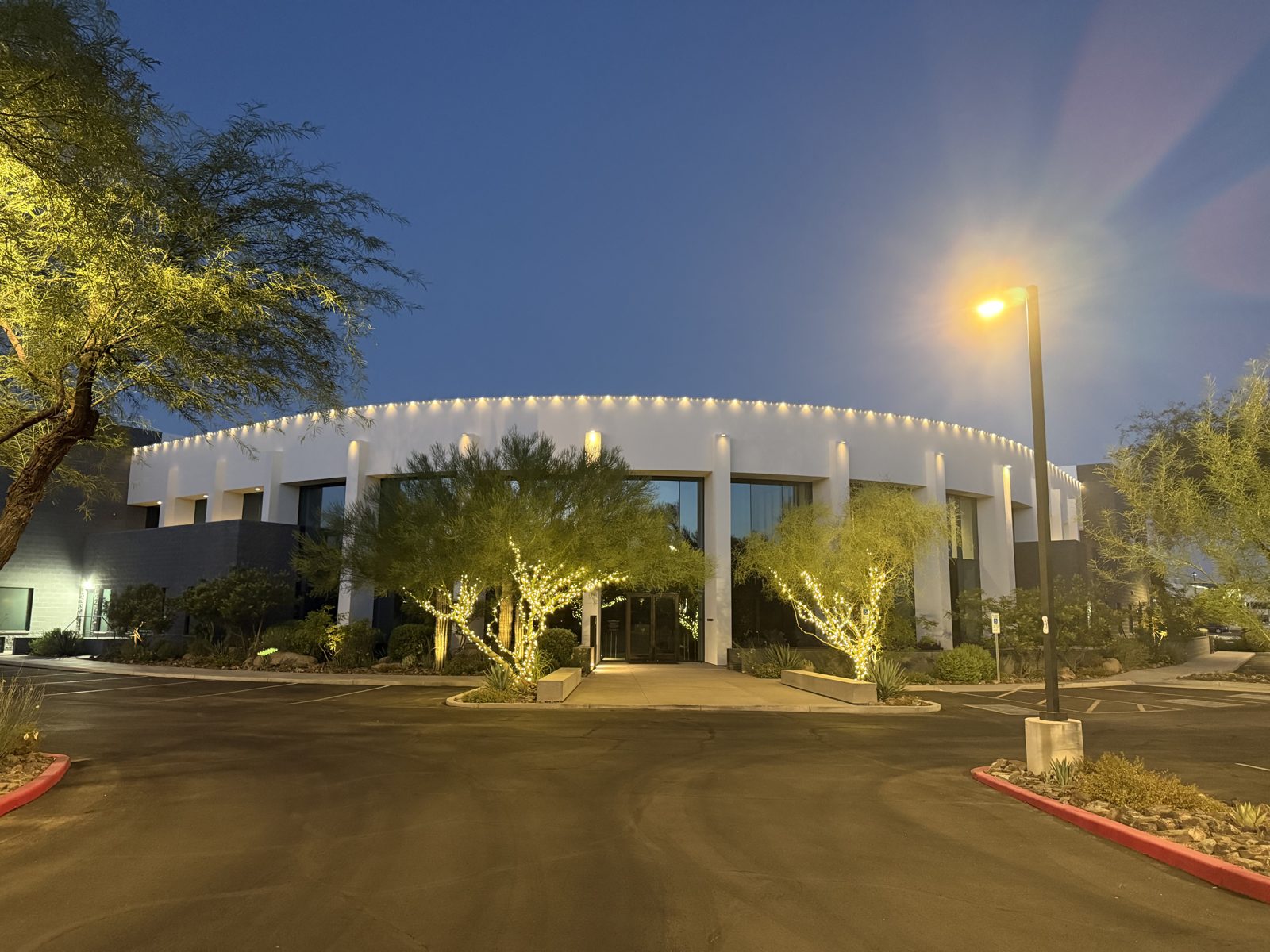 Warm white permanent roofline lighting on a curved commercial building at dusk