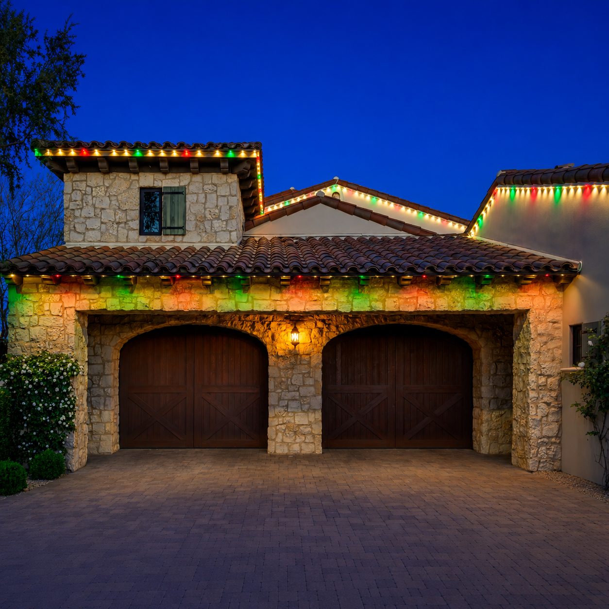 Multicolor Gemstone roofline lighting mounted to the fascia under a tile roof above a stone garage