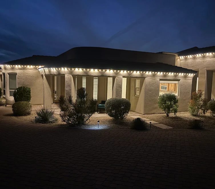 Warm white permanent roofline lighting on a single-story Arizona home with no eaves, mounted along the wall edge